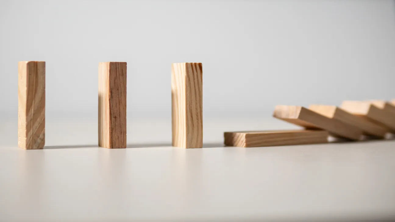 Three wood blocks standing upright as others fall