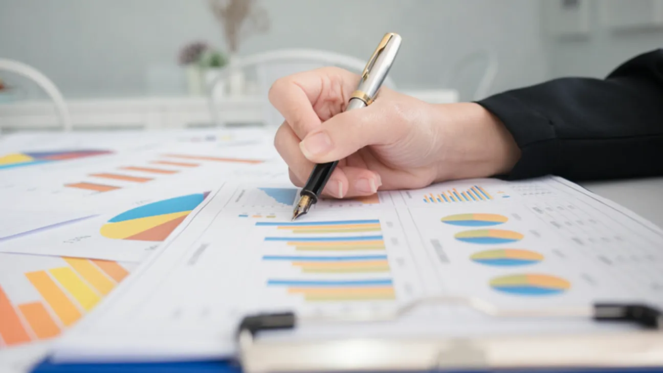 A womans hand writing on pages of graphs